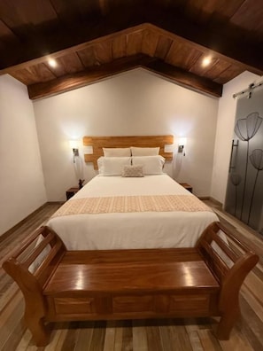A bedroom with a wooden bed, nightstands, and a bench. - Bärehuus Boutique Hotel (Antigua Guatemala)
