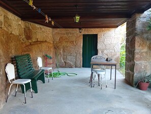 Een overdekt terras met stenen muren, een houten plafond en een groene deur.