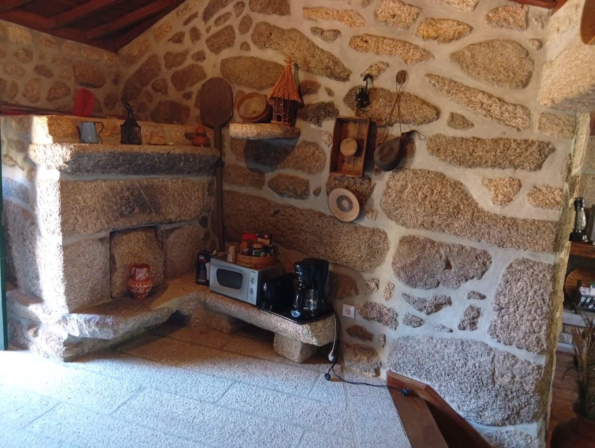 A stone-walled room with a fireplace, a kettle, and a coffee maker.