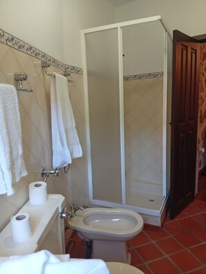 Een badkamer met toilet, bidet en douchecabine.