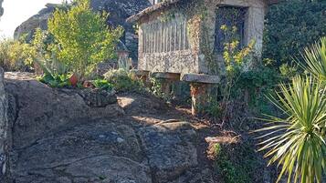 Un bâtiment rustique en pierre, doté d’un toit en pente, entouré de verdure et situé dans un environnement rocheux.