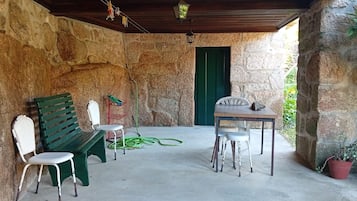 A covered outdoor seating area with stone walls, a wooden ceiling, and a green door.