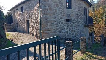 A stone building with a fenced entrance, a small window, and a door.