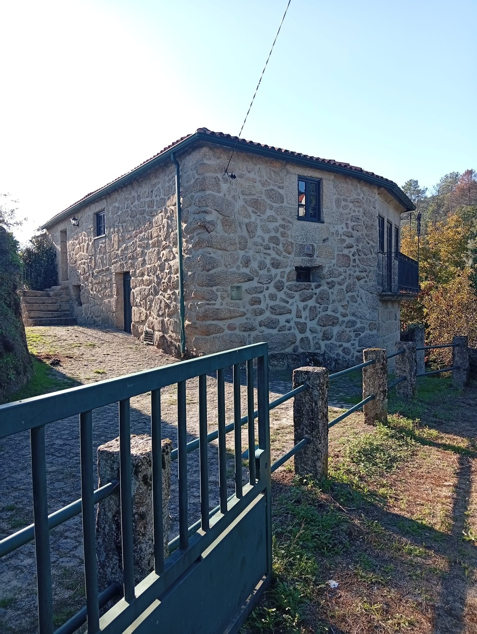 A stone building with a fenced entrance, a small window, and a door.