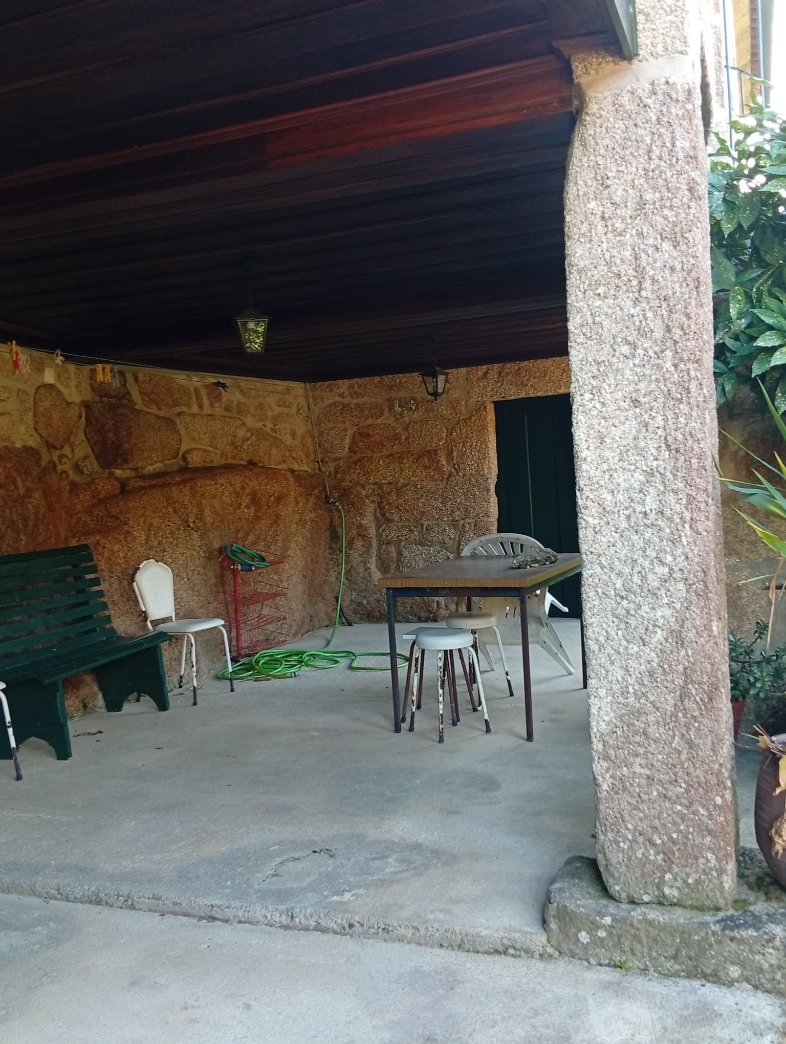 An outdoor seating area with a stone wall backdrop, a table, and chairs.