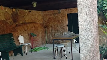 An outdoor seating area with a stone wall backdrop, a table, and chairs.