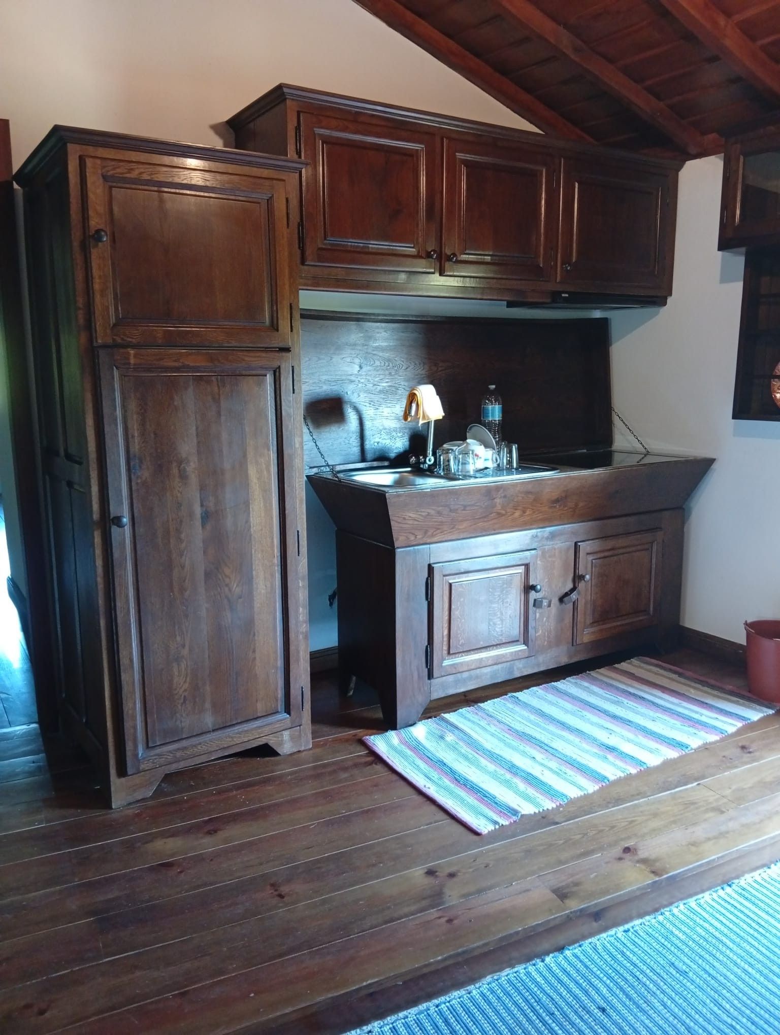 Une cuisine avec des meubles de rangement en bois, un plan de travail et un luminaire suspendu.