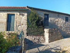 Edifici de pedra amb dues finestres, una reixa metàl·lica i una petita zona de jardí.