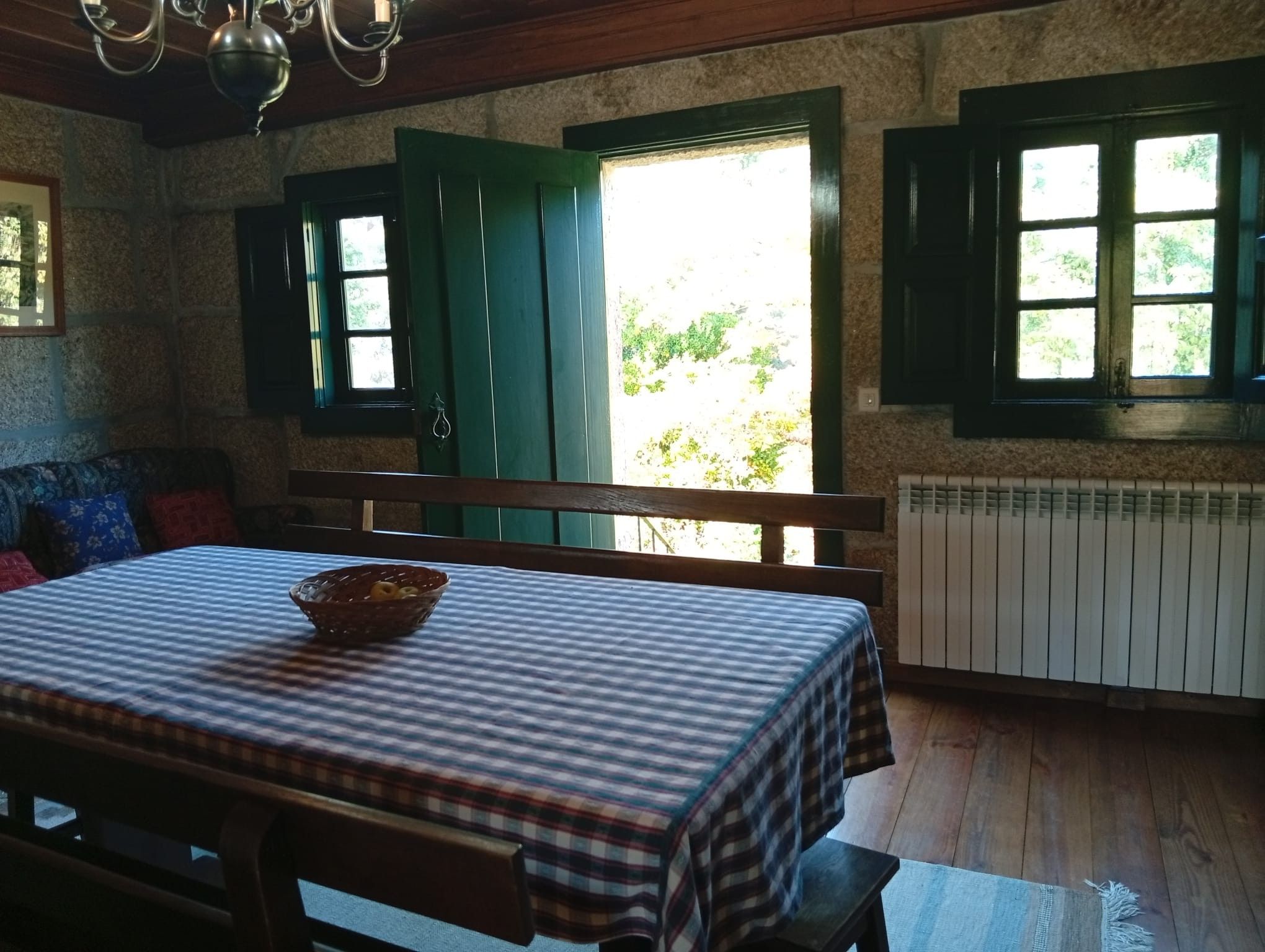A room with a wooden table, a bench, and a window with shutters.