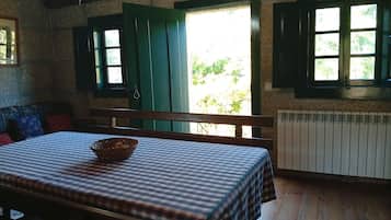 A room with a wooden table, a bench, and a window with shutters.
