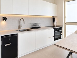 Una cocina moderna con armarios blancos, un lavavajillas negro, una estufa y un fregadero.