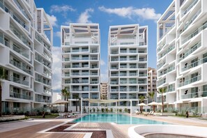 Un hotel moderno con varios pisos, una piscina central y zonas de estar al aire libre.