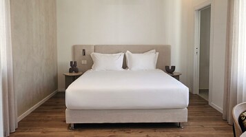 A neatly made bed with a headboard, two bedside tables, and a door to the right.