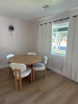 Ein Essbereich mit einem runden Holztisch und vier weißen Stühlen.