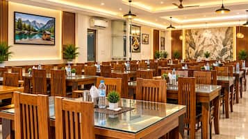 A spacious dining area with multiple tables and chairs, ceiling fans, and pendant lighting.