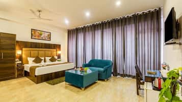 A hotel room with a bed, a sofa, a coffee table, a TV, and a large window with curtains.