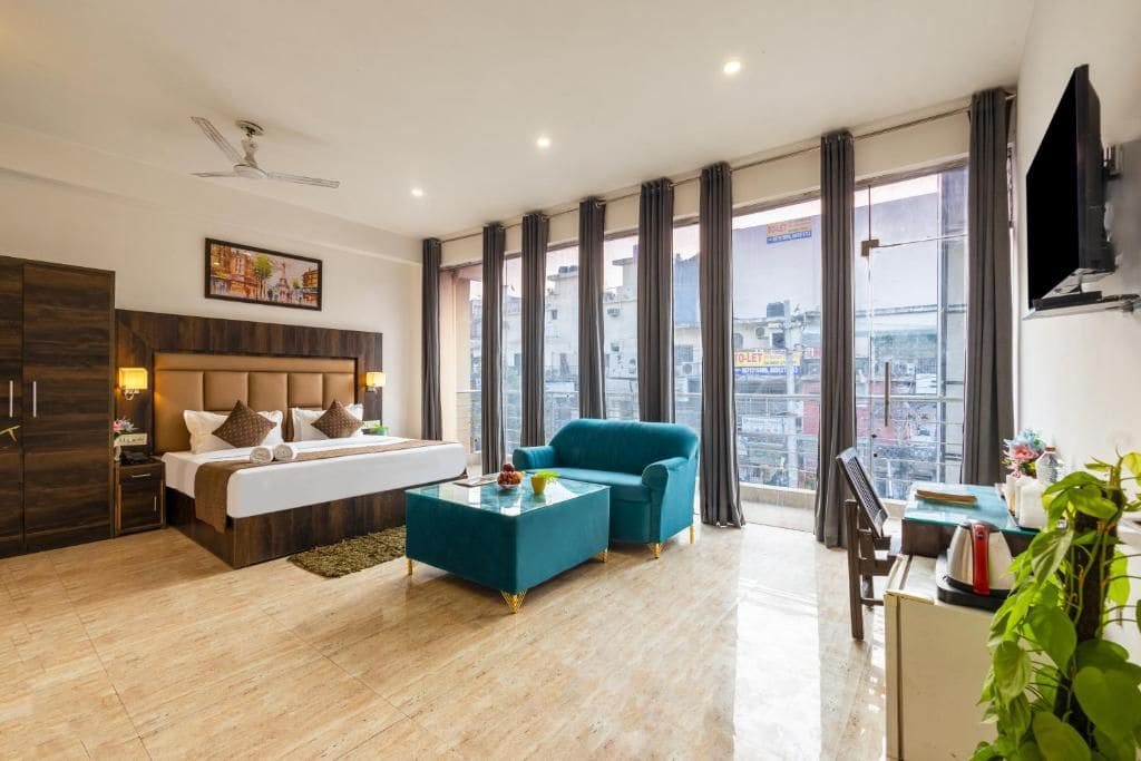 Ein Hotelzimmer mit Bett, einer Couch, einem Couchtisch, einem Schreibtisch und Blick auf die Stadt.