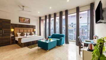 Ein Hotelzimmer mit Bett, einer Couch, einem Couchtisch, einem Schreibtisch und Blick auf die Stadt.