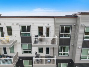 A multi-story residential building with balconies, large windows, and a flat roof. - `Auburn` 1 King  1 Queen Bed | UG Parking | Sofa Bed (Calgary)