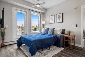 Un dormitorio con cama, mesita de noche, ventilador de techo y ventana con vistas.