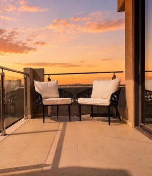 A balcony with two chairs and a glass partition. - Sunrise & Sunset 1BR | 5 Min to Eagle Beach (Noord)