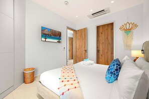 Enjoy a quiet evening with the bedroom’s wall-mounted TV and air conditioning, surrounded by colorful textiles and woven accents. - Sunrise & Sunset 1BR | 5 Min to Eagle Beach (Noord)