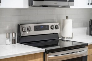 A modern kitchen with a stainless steel LG stove, a digital display, and a paper towel dispenser. - `Boston` King Bed | Private Suite + 7 Min to DT (Calgary)