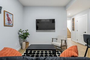 A living room with a flat-screen TV, a sofa, a chair, and a coffee table. - `Boston` King Bed | Private Suite + 7 Min to DT (Calgary)