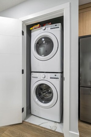 A compact laundry room with two stacked front-loading washing machines. - `Boston` King Bed | Private Suite + 7 Min to DT (Calgary)