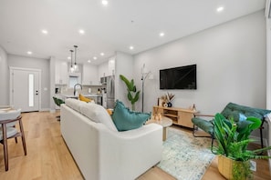 A modern living room with a sofa, a coffee table, and a TV mounted on the wall. - The Evergreen | 3 Bed | Garage | Min to Hospital (Calgary)