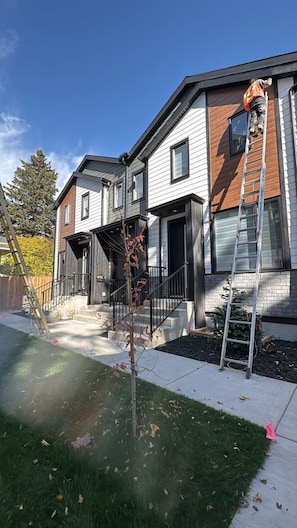 A residential building with a modern design, featuring a front porch and a visible staircase leading to the entrance. - The Evergreen | 3 Bed | Garage | Min to Hospital (Calgary)