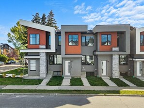 Un edificio residencial moderno de varios pisos con fachada uniforme, ventanas amplias y un césped cuidado.