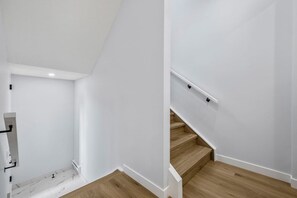 A staircase with wooden steps and white walls, leading to an upper floor. - `The Juniper` 3 Bed | King | Garage | 5 Min to DT (Calgary)