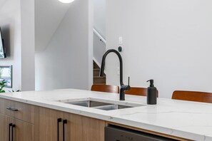 A modern kitchen with a white countertop, black faucet, and a single bottle of soap. - `The Juniper` 3 Bed | King | Garage | 5 Min to DT (Calgary)
