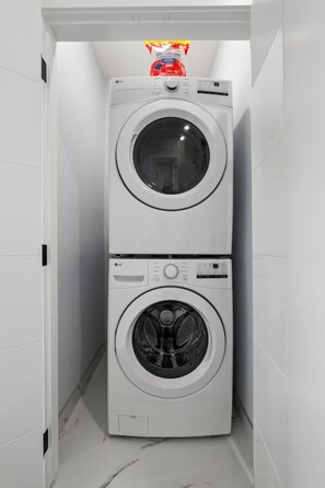 A compact, white, two-door laundry room with a small shelf above the top door. - ‘Rowan’ 3 Bed | Garage | King + 7 Min to DT (Calgary)