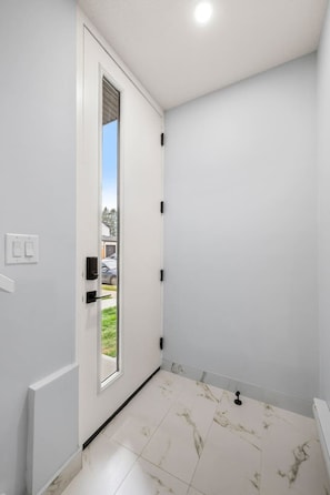A room with a white door, a window, and a tiled floor. - ‘Rowan’ 3 Bed | Garage | King + 7 Min to DT (Calgary)