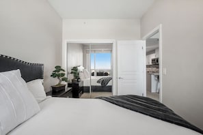 A bedroom with a bed, bedside tables, a potted plant, and a view of a balcony. - `Skyline` Downtown Core | AC | Walk to Saddledome (Calgary)