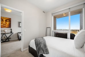 A bedroom with a bed, a desk, a chair, a painting, and a window with a view. - `Skyline` Downtown Core | AC | Walk to Saddledome (Calgary)