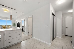 A modern kitchen with a large island, a dining area with a view, and a hallway leading to bedrooms. - `Skyline` Downtown Core | AC | Walk to Saddledome (Calgary)