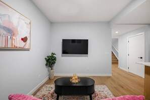 A modern living room with a flat-screen TV, a potted plant, and a black coffee table. - `Paris` King Bed | 7 Mins to DT + Free Parking (Calgary)
