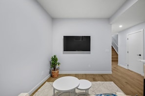 A modern, minimalistic room with a white wall, a small window, a potted plant, and a round table. - `Greece` King Bed | Private Suite + 7 Min to DT (Calgary)