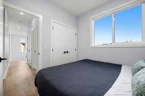 Un dormitori amb un llit, una finestra i una porta que dona a una altra habitació.