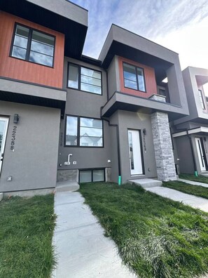 A modern multi-story residential building with a flat roof, large windows, and a stone accent wall. - `Jade` 3 King Bedrooms | Garage + 7 Min to DT (Calgary)