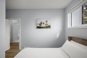 A bedroom with a bed, a window, and a wall-mounted picture. - `Jade` 3 King Bedrooms | Garage + 7 Min to DT (Calgary)