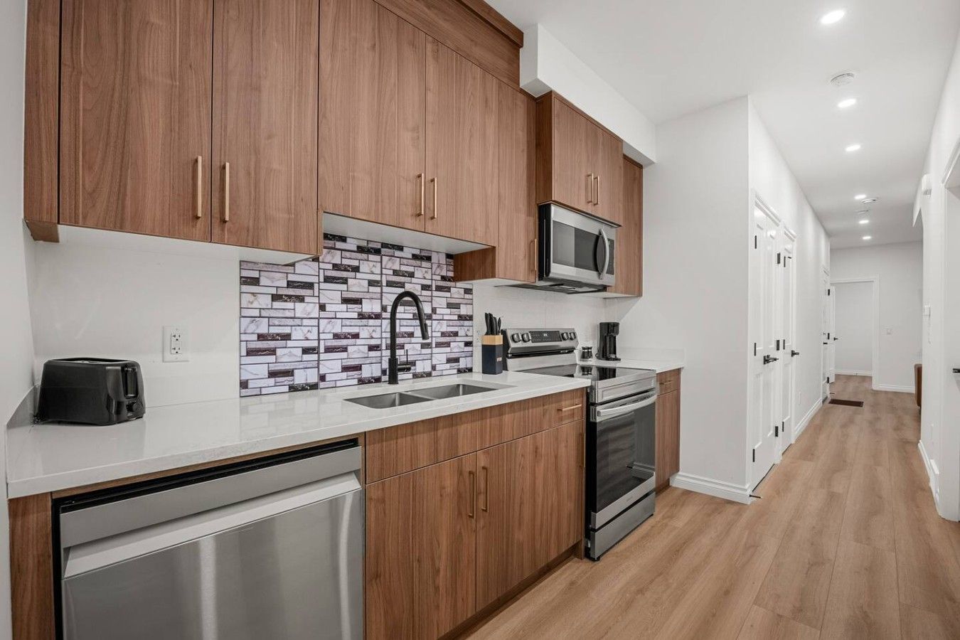 A modern kitchen with wooden cabinets, a stainless steel dishwasher, a microwave, and a stove.