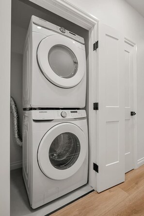 Una col·locació de rentadora i assecadora en un passadís amb una porta tancada a la dreta.