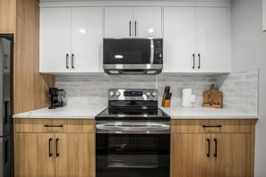 A modern kitchen with stainless steel appliances, wooden cabinets, and a marble countertop. - `Stampede` King Bed | 7 Min to Downtown + Parking (Calgary)