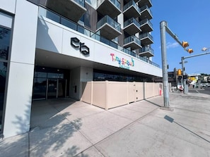 A modern building with a storefront labeled 'Tiny Sprouts Childcare' and a gated entrance. - The Ivory | 2 Bedroom | UG Parking | Rooftop Patio (Calgary)