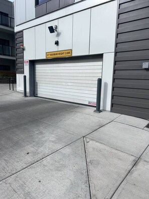 A garage door with a height restriction sign, a security camera, and a fire hydrant. - The Ivory | 2 Bedroom | UG Parking | Rooftop Patio (Calgary)