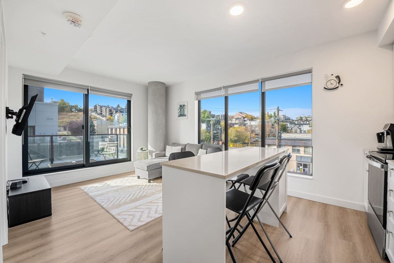 A modern apartment with large windows, a kitchen, and a dining area.